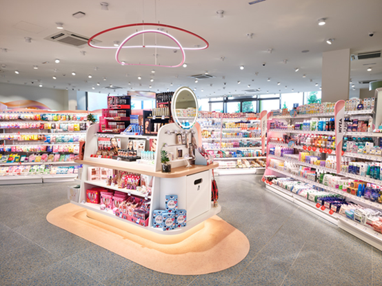 Interno del negozio luminoso e moderno con scaffali ordinati che espongono cosmetici e prodotti per la cura della pelle colorati sotto illuminazione circolare.