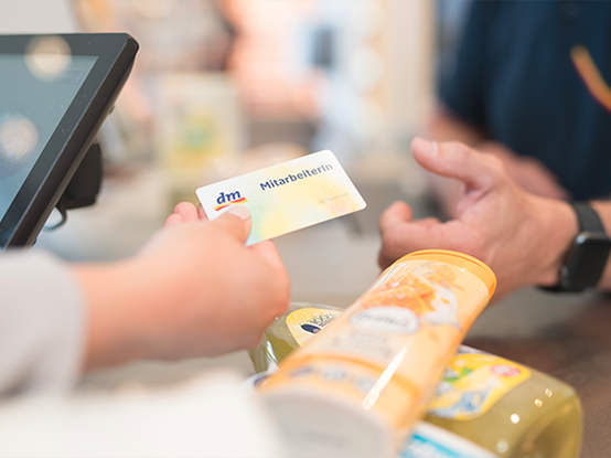 Una persona sta consegnando una carta di identificazione al banco cassa, mentre vari prodotti sono posizionati sul bancone.