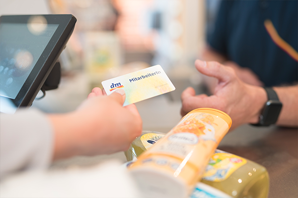 Una persona sta consegnando una carta di identificazione al banco cassa, mentre vari prodotti sono posizionati sul bancone.