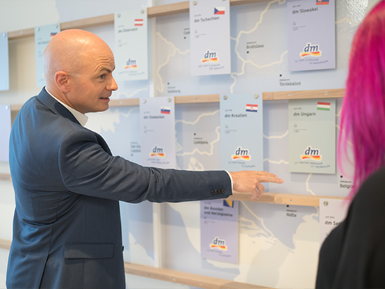 Una persona indica informazioni su una mappa o un pannello informativo, mentre un'altra persona ascolta attentamente.