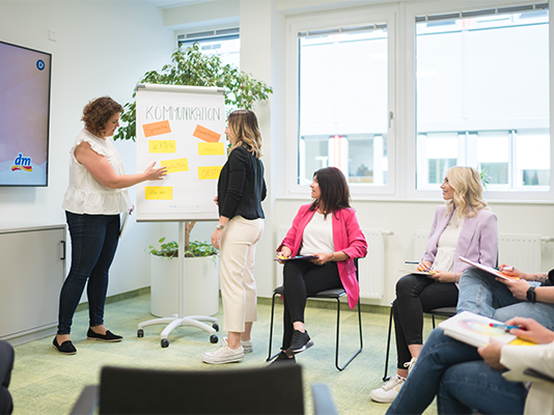 Una persona presenta idee su un foglio di carta in una riunione, mentre altri partecipanti ascoltano e prendono appunti.