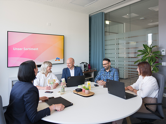 Persone in riunione esaminano prodotti e discutono in armonia.